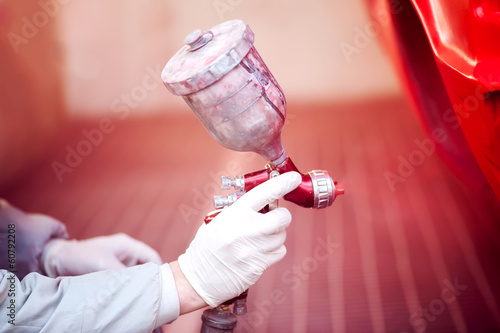 Worker painting a red car in paiting booth photo