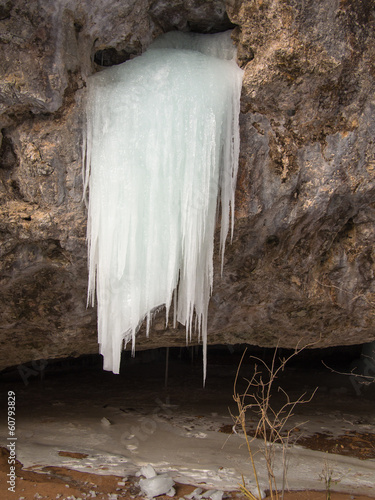Icicles are growing from a hole in the rock on sand background
