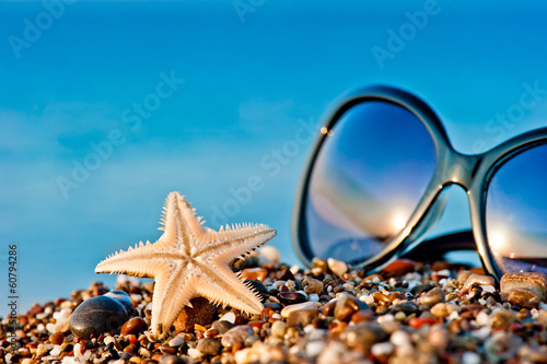 Starfish and sunglasses on the beach against the sea © kosmos111