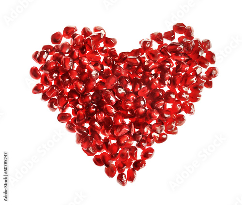 Red heart made of pomegranate seeds on white background