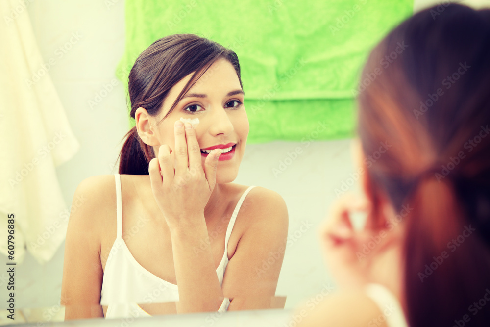 Beautiful woman applying cream on face Beautiful woman applying cream on face
