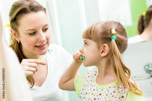 mother and child daughter brushing teeth in bathroom