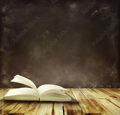 One book on table in front of black board background