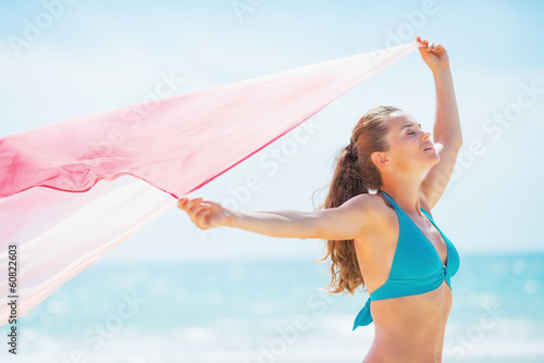 Happy young woman with parero rejoicing on beach