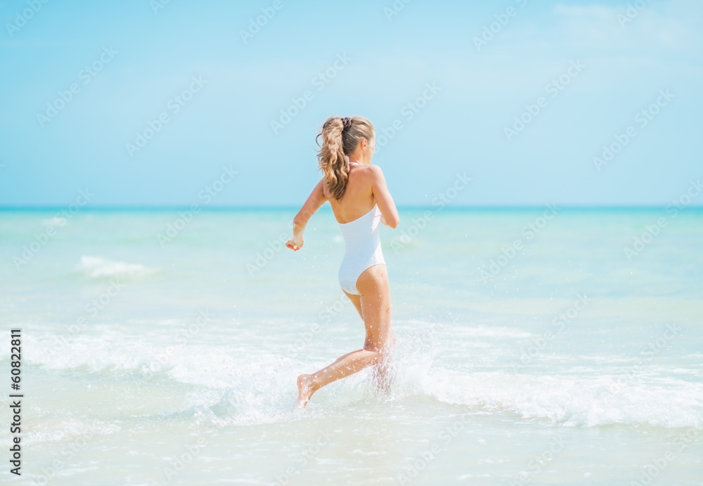 Young woman in swimsuit running into sea