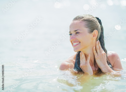 Happy young woman standing in sea looking on copy space
