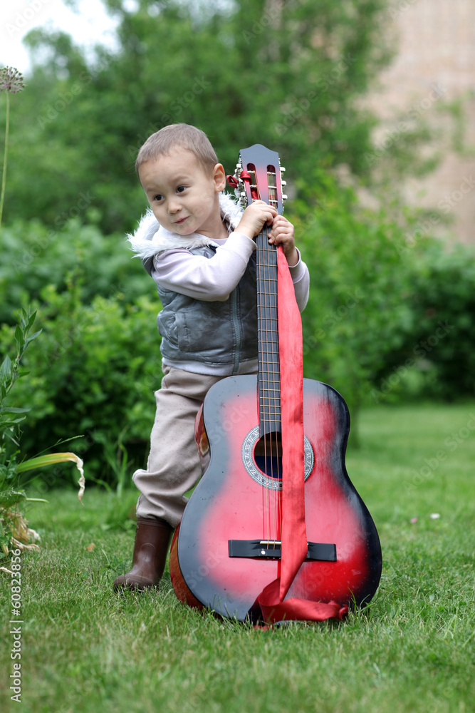 Fototapeta premium little boy with guitar outdoors