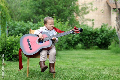 little boy very passionary play in guitar outdoors