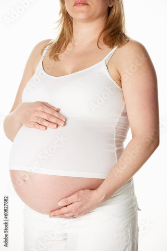 Close Up Studio Portrait Of 8 Months Pregnant Woman Wearing Whit © Monkey Business
