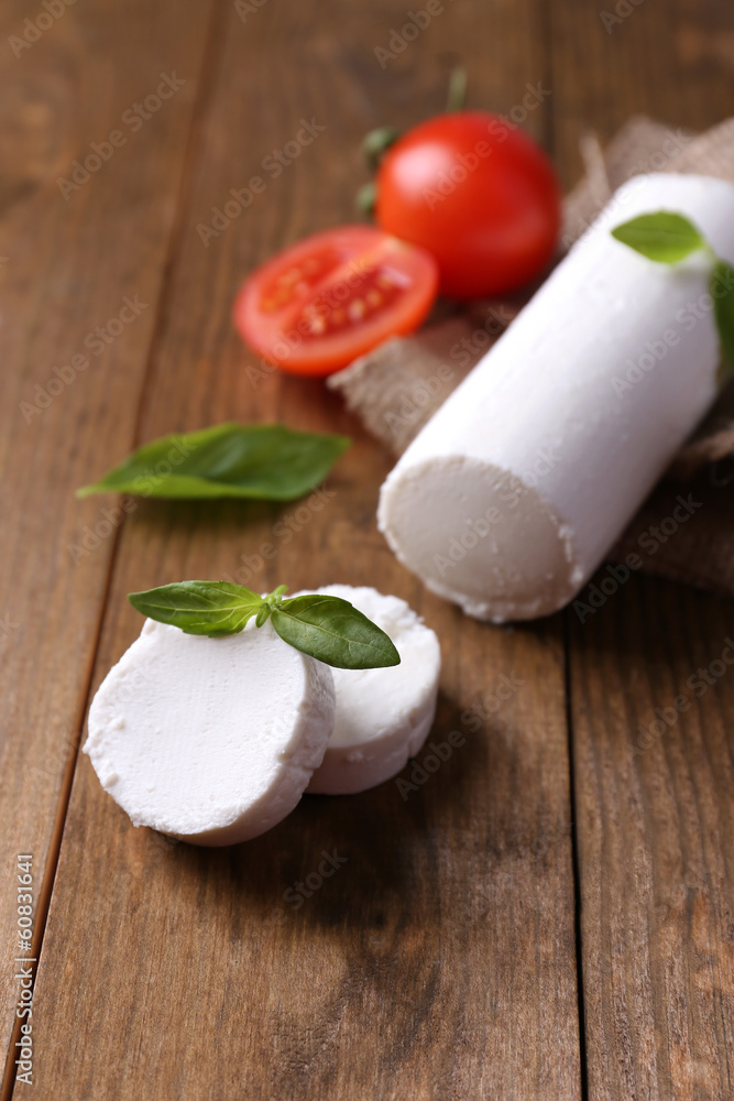 Tasty bushe cheese with basil and tomato, on wooden table Tasty bushe cheese with basil and tomato, on wooden table