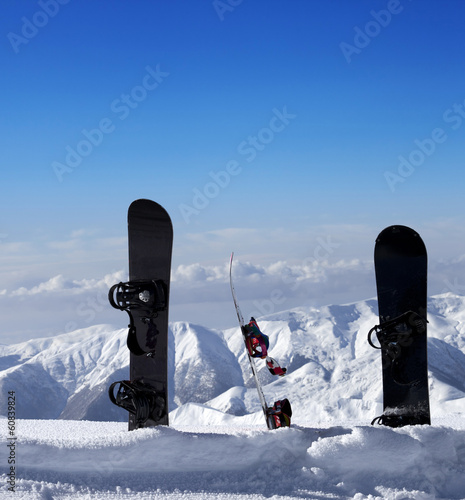 Three snowboards in snow near off piste slope in sun day