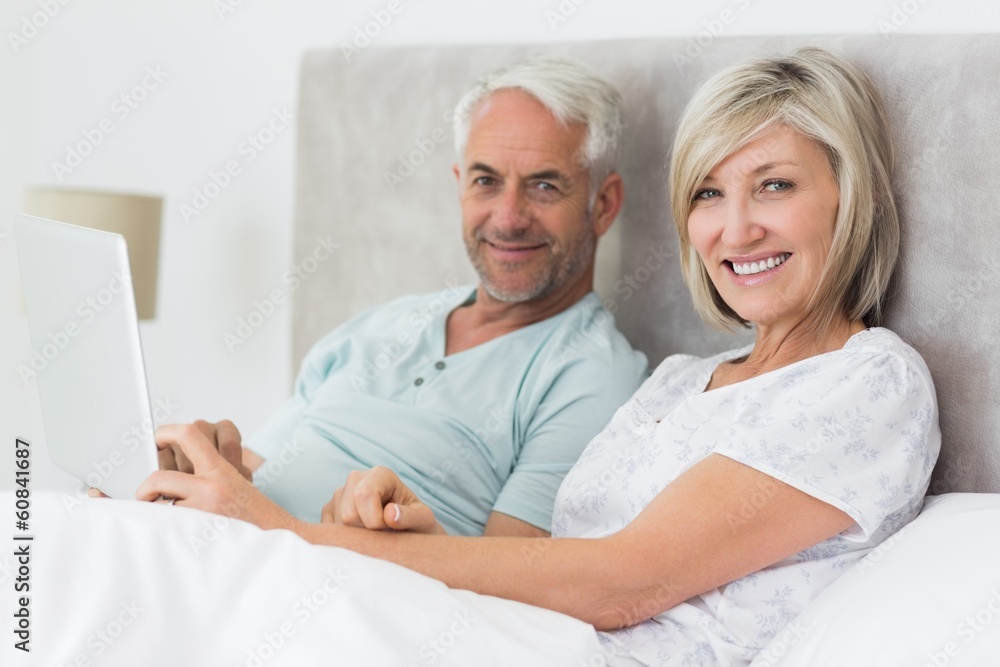 Happy mature couple using digital tablet in bed Happy mature couple using digital tablet in bed