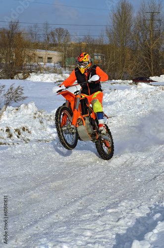 Winter motocross rider riding a wheelie through the snow