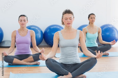 Women in meditation pose with eyes closed at fitness studio