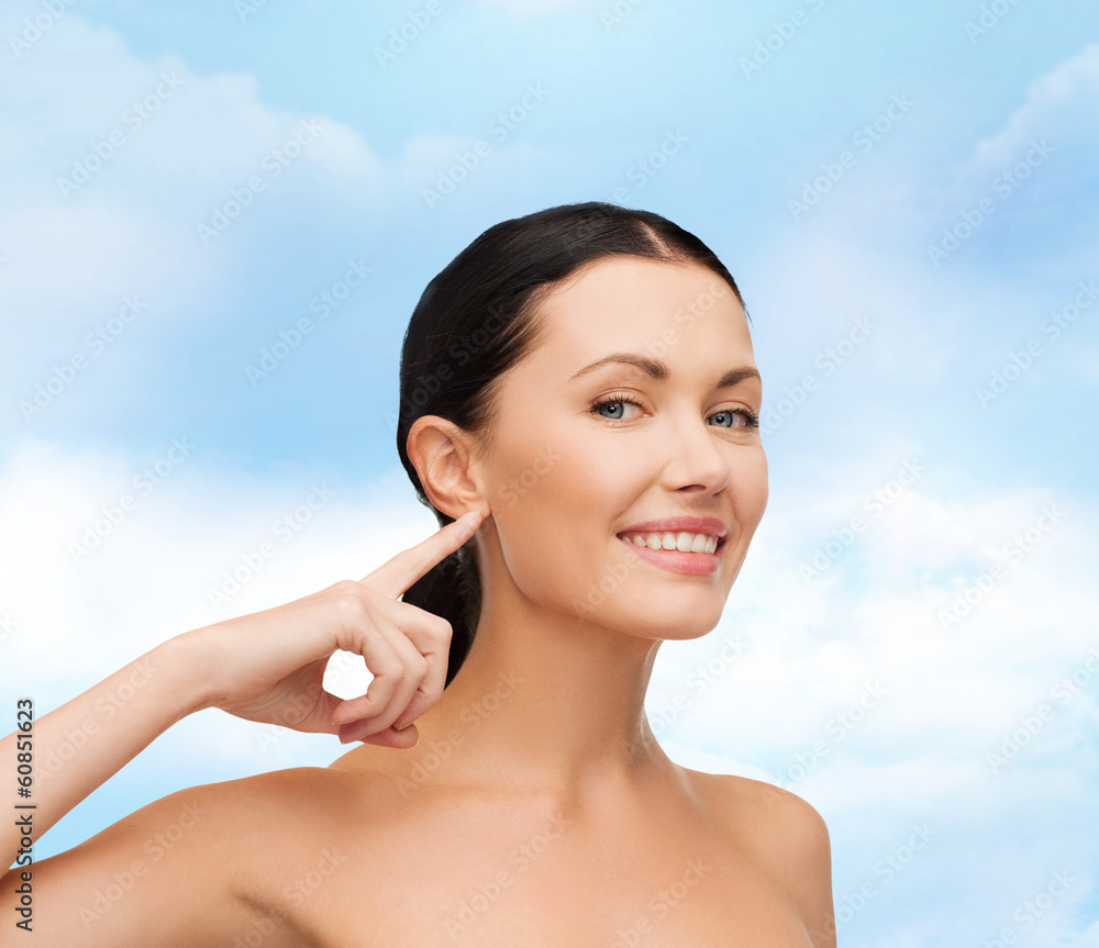 young calm woman pointing to her ear young calm woman pointing to her ear