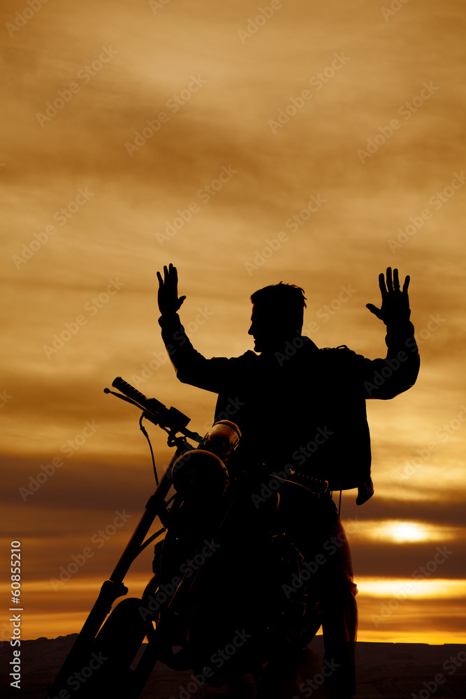 silhouette of a man on a motorcycle hands up
