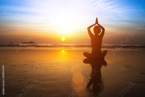 Yoga woman sitting on sea coast at sunset. © De Visu