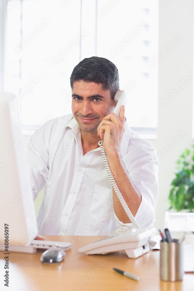 Businessman using landline phone and computer Businessman using landline phone and computer