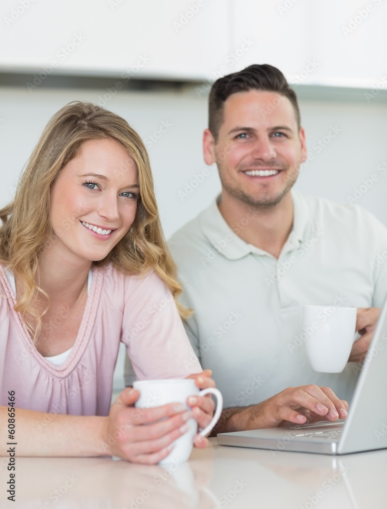 Couple with coffee mugs and laptop sitting at table Couple with coffee mugs and laptop sitting at table