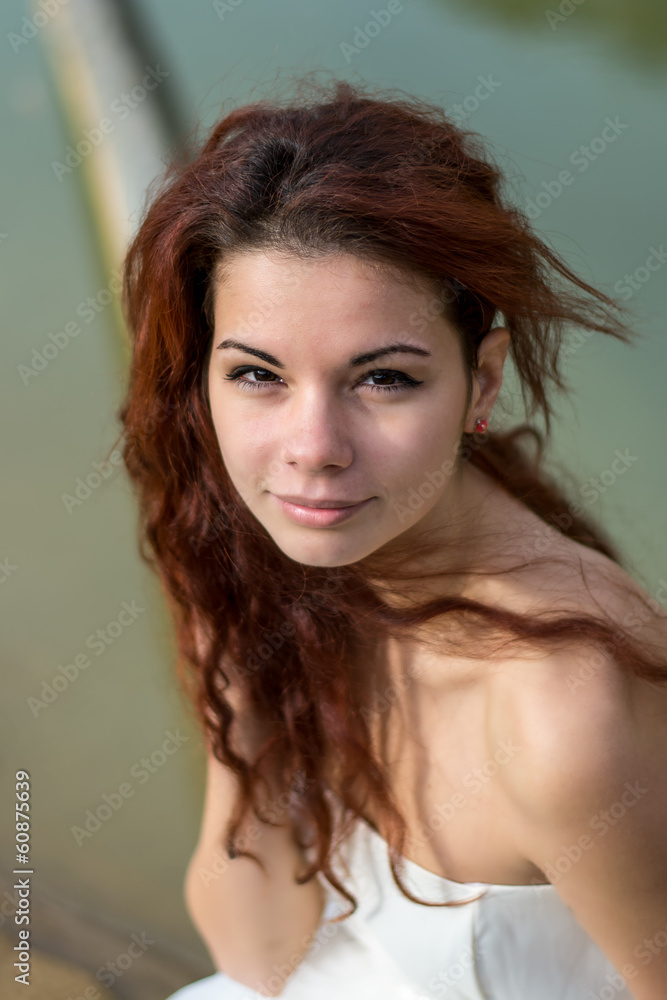 portrait of beautiful red hair girl posing near a turquoise lake