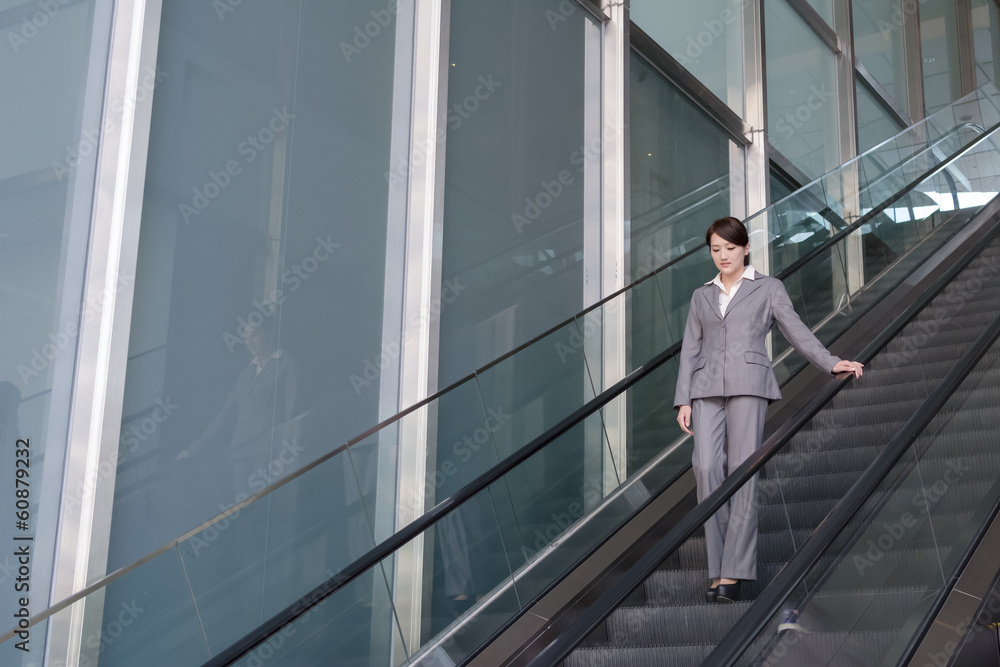 Asian business woman stand at escalator