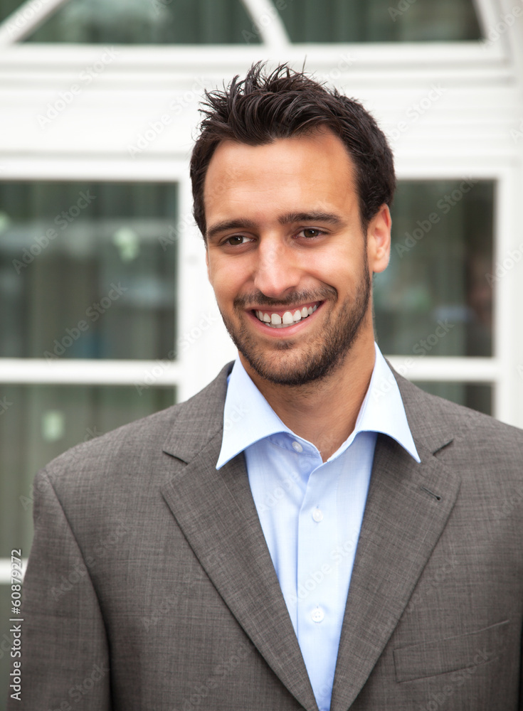 Handsome latin businessman laughing in front of his office