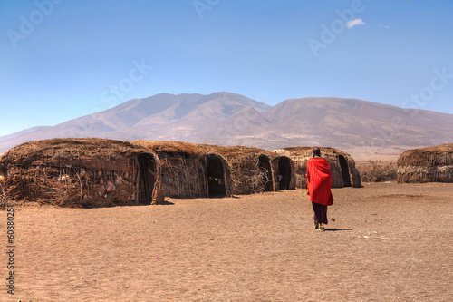 Obraz na płótnie Massai huts with a woman in red in back view w salonie
