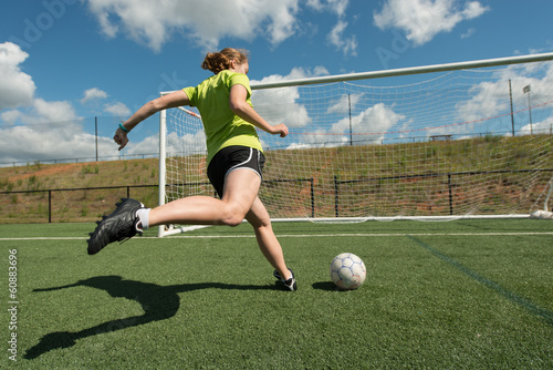 Female soccer player shooting on goal wide low angle
