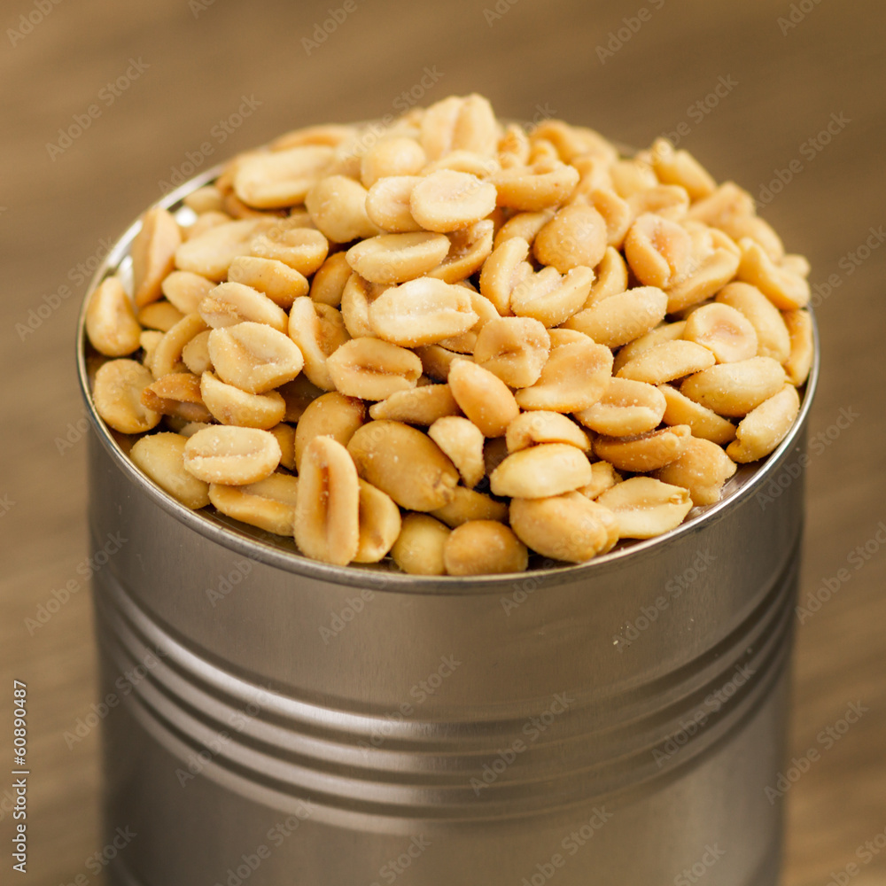 salted peanuts, nuts in a small metal bowl with wood background salted peanuts, nuts in a small metal bowl with wood background