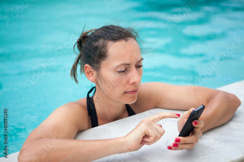 Frau mit Smartphone im Pool