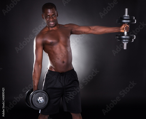 Young African Man Working Out With Dumbbells