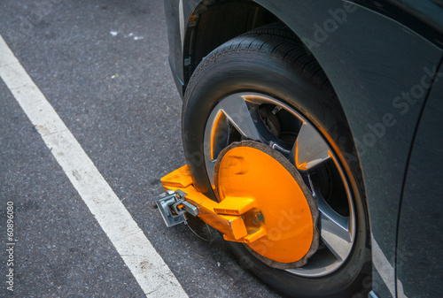 Yellow wheel clamp locked with messing lock on an illegally park
