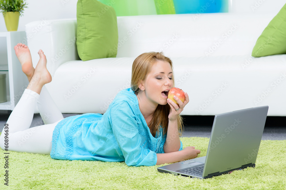 Fototapeta premium woman relaxing with an apple in front of her laptop.