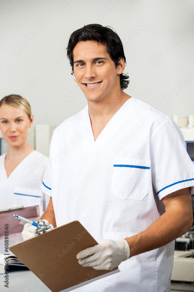 Male Researcher Holding Clipboard In Lab Male Researcher Holding Clipboard In Lab