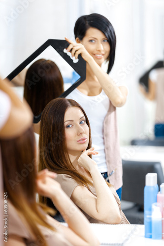 Beautician showing the ready haircut of the female client