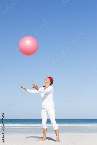 Mature woman catching gymnastic ball at beach