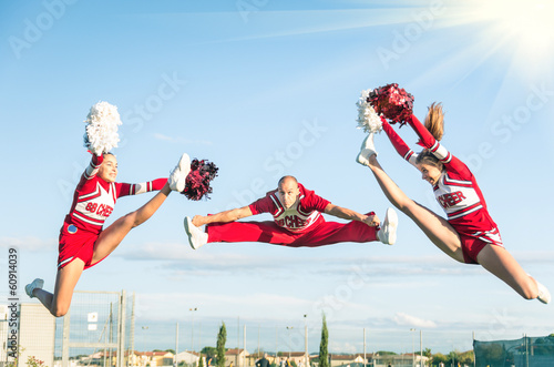 Cheerleaders team performing a Jump with male Coach