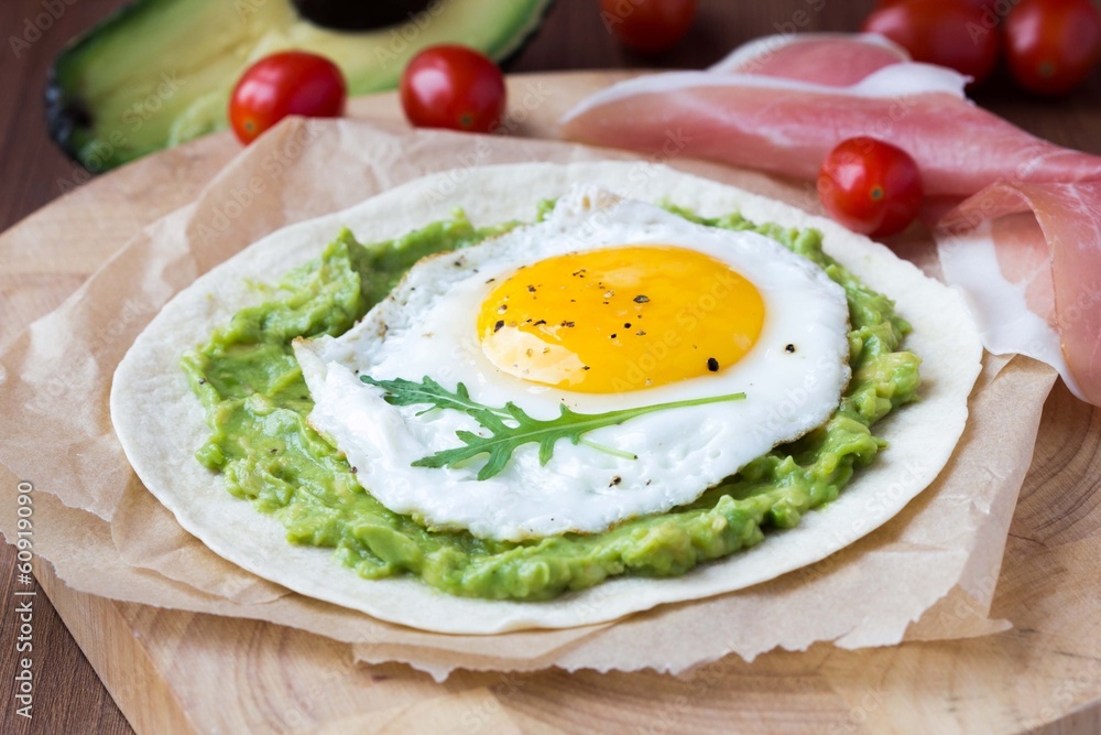 Breakfast with fried egg and sauce of avocado on grilled flour Breakfast with fried egg and sauce of avocado on grilled flour