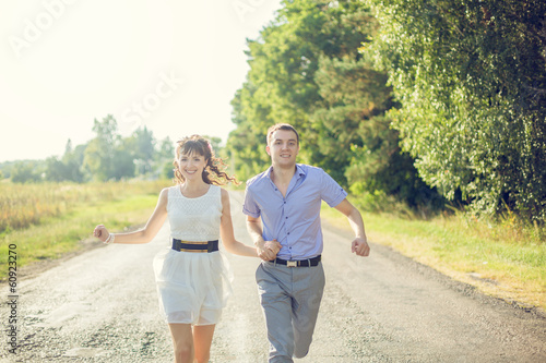 Girl with a guy running down the road holding hands