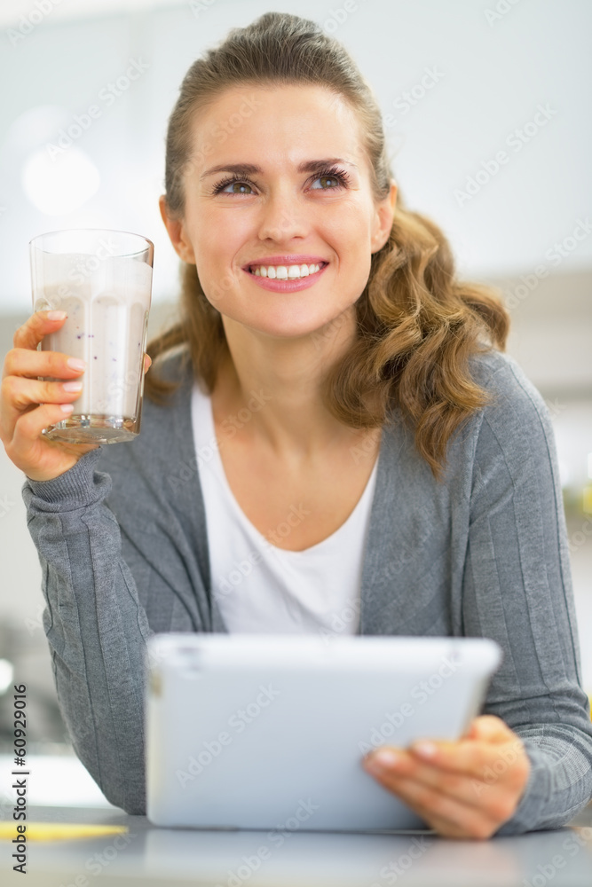 Thoughtful young woman with smoothie using tablet pc Thoughtful young woman with smoothie using tablet pc