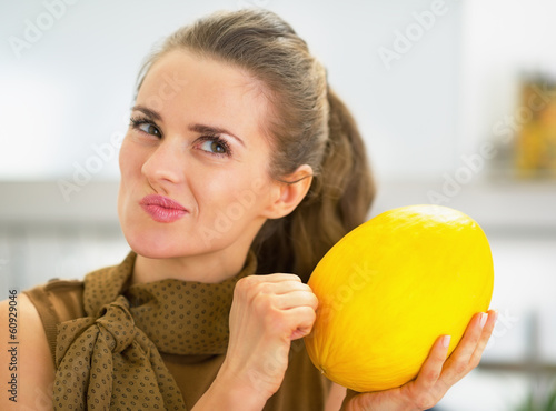 Happy young housewife checking ripeness of melon photo