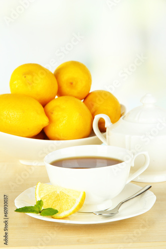 Cup of tea with lemon on table on light background