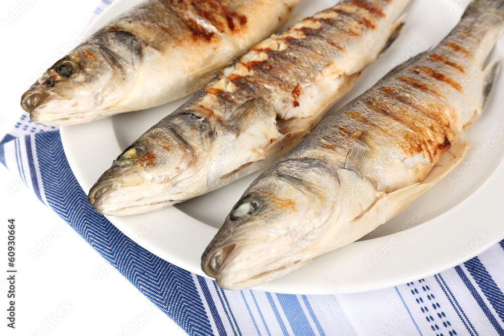 Delicious grilled fish on plate on table close-up Delicious grilled fish on plate on table close-up