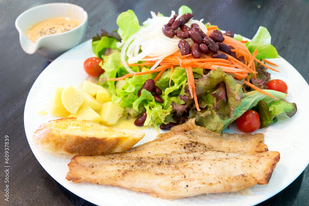 Fish steak with salad, dipping sauce and garlic bread Fish steak with salad, dipping sauce and garlic bread