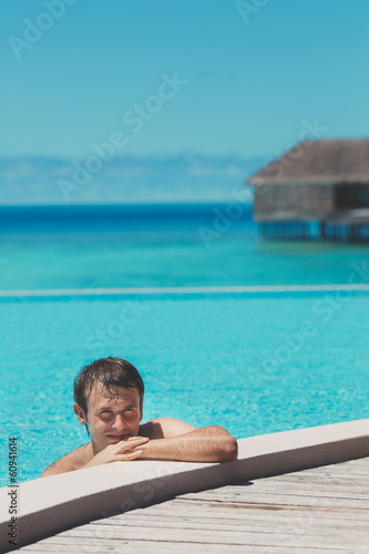 Young man in the pool and ocean in the background. Maldives