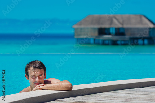 Young man in the pool and ocean in the background. Maldives