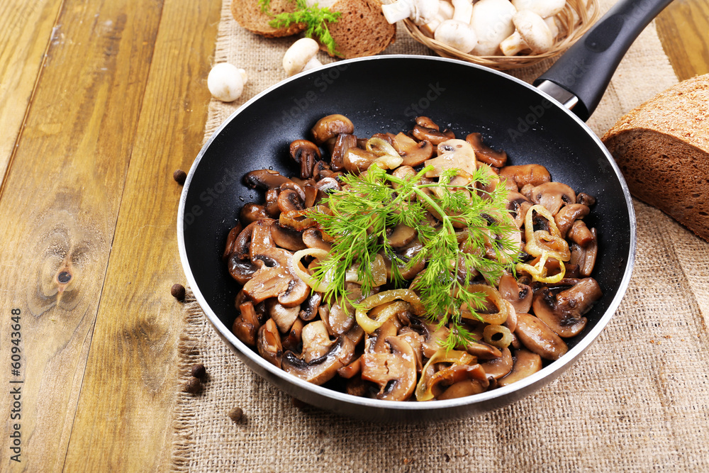 Delicious fried mushrooms in pan on table close-up Delicious fried mushrooms in pan on table close-up