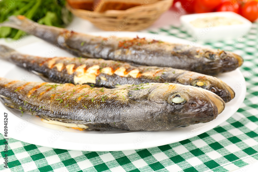 Delicious grilled fish on plate on table close-up Delicious grilled fish on plate on table close-up