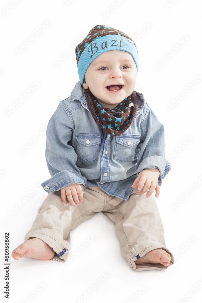 Kleiner Bub mit süßer Mütze, sitzt, lacht, freigestellt Kleiner Bub mit süßer Mütze, sitzt, lacht, freigestellt