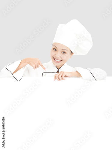 smiling young woman chef pointing with blank board